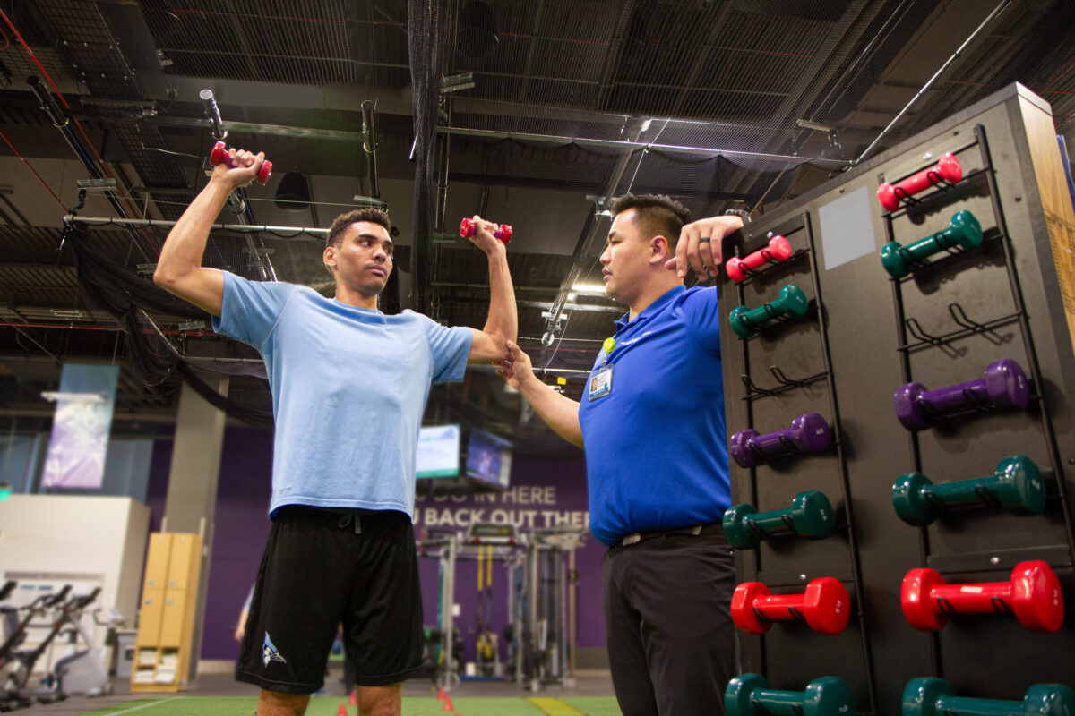 Sports Medicine physical therapist assisting member with free weights